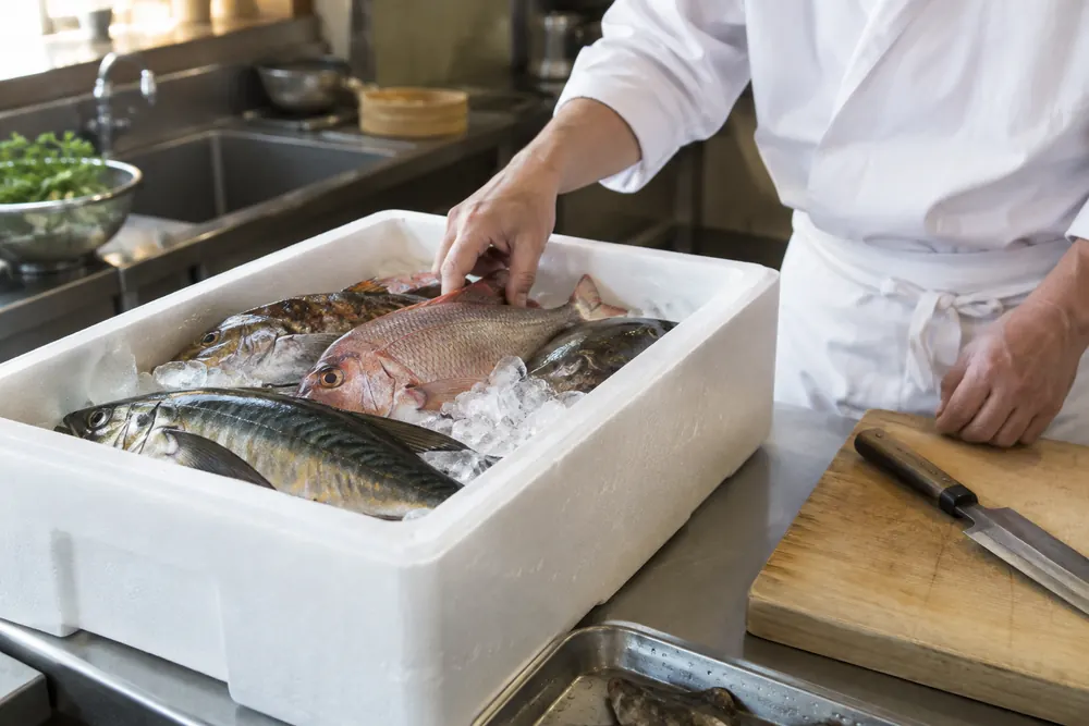 飲食店の厨房に届いた鮮魚の箱のイメージ